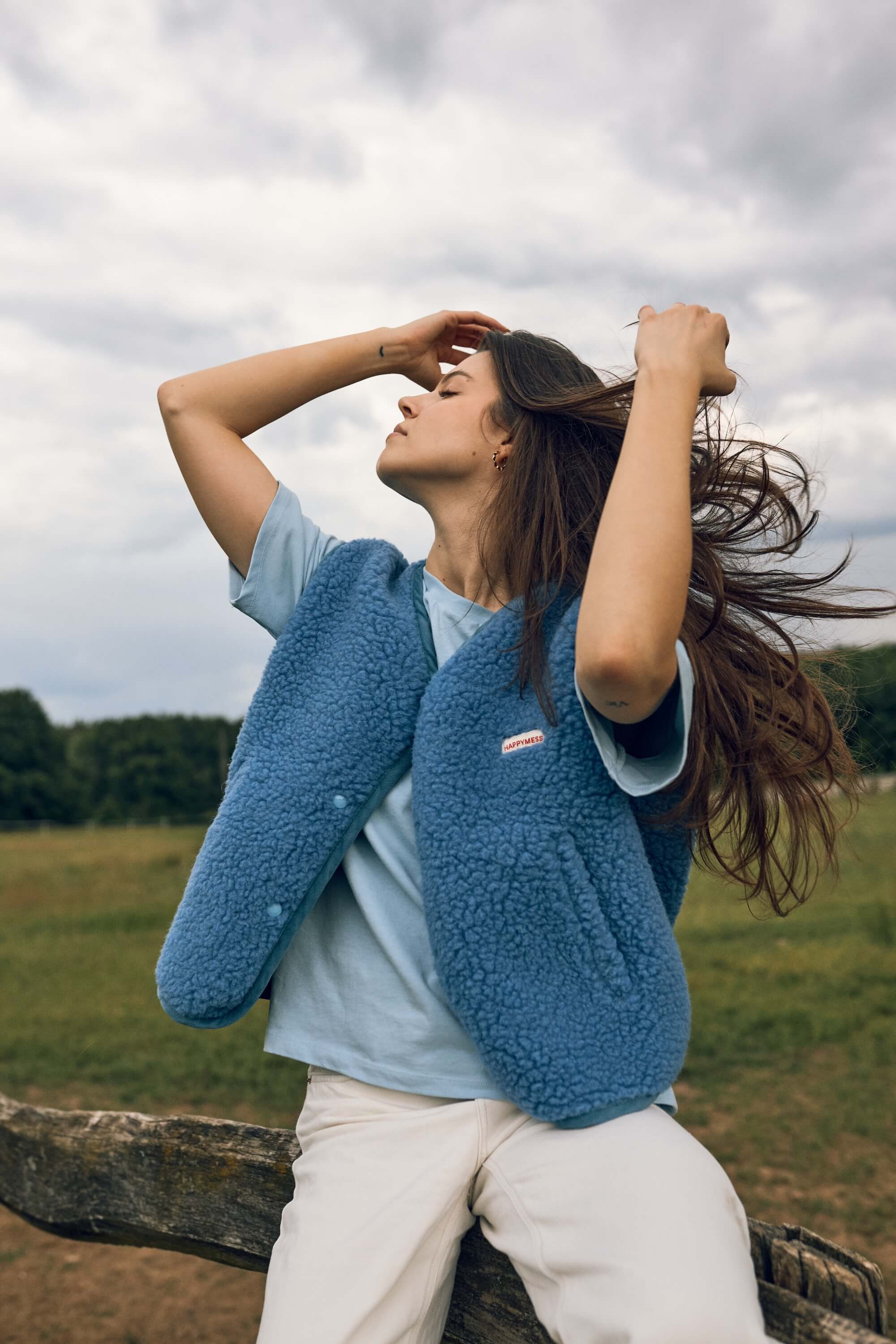 Woman wearing a blue knit vest with a visible brand logo
