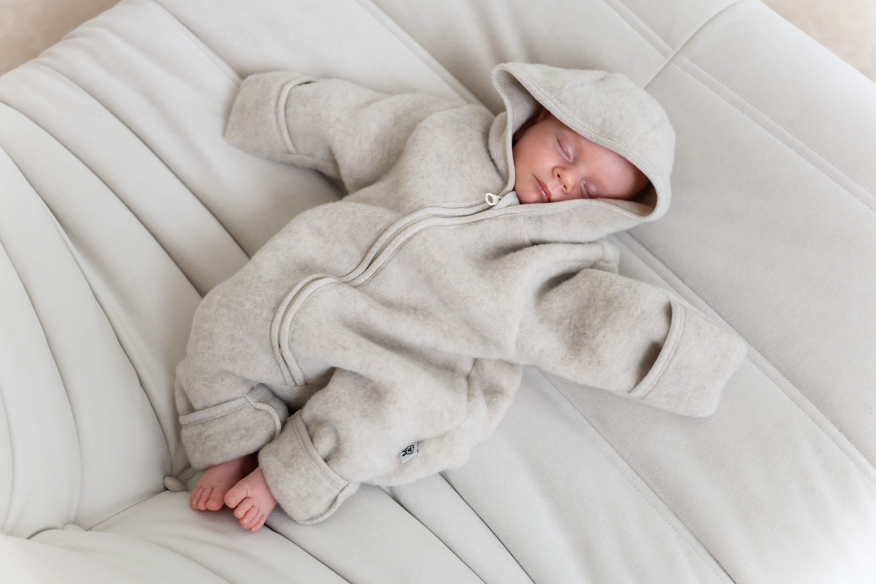 Newborn baby wearing a gray hooded onesie