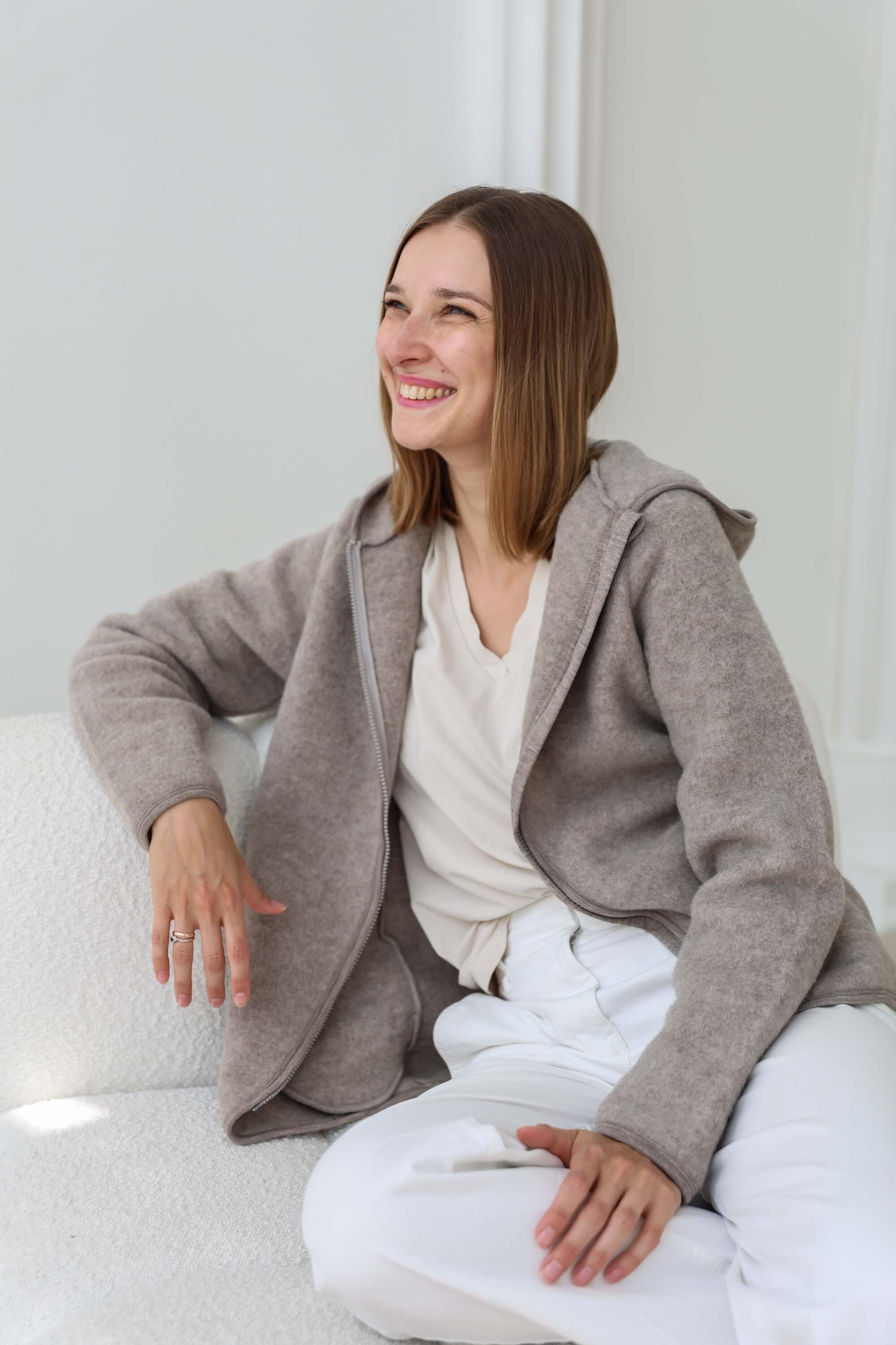 Woman wearing a gray cardigan over a white top and pants
