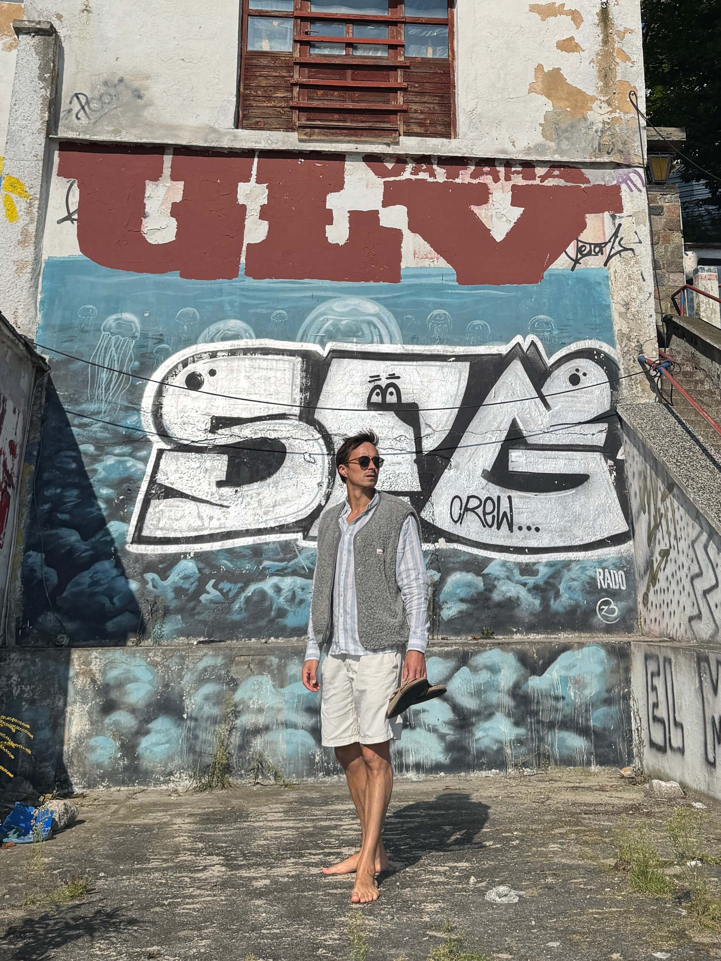 Man standing in front of a graffiti-covered wall with large letters