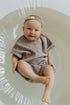 Baby in a pink outfit sitting in a white circular chair