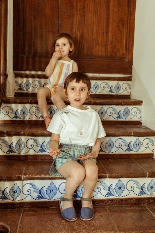 Two children sitting on a decorative staircase with floral tile patterns.