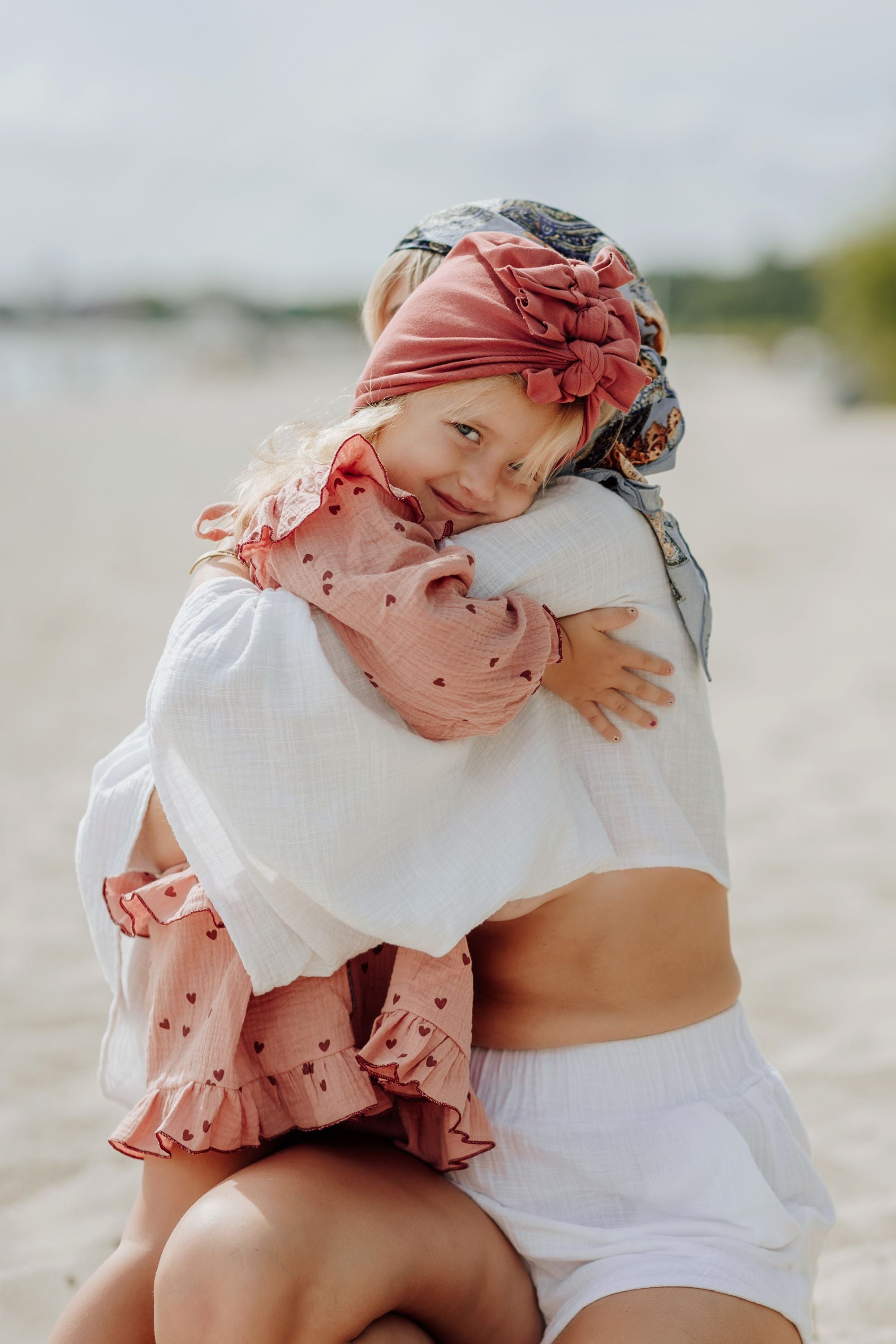 A girl and her mom holding each other on the beach.
