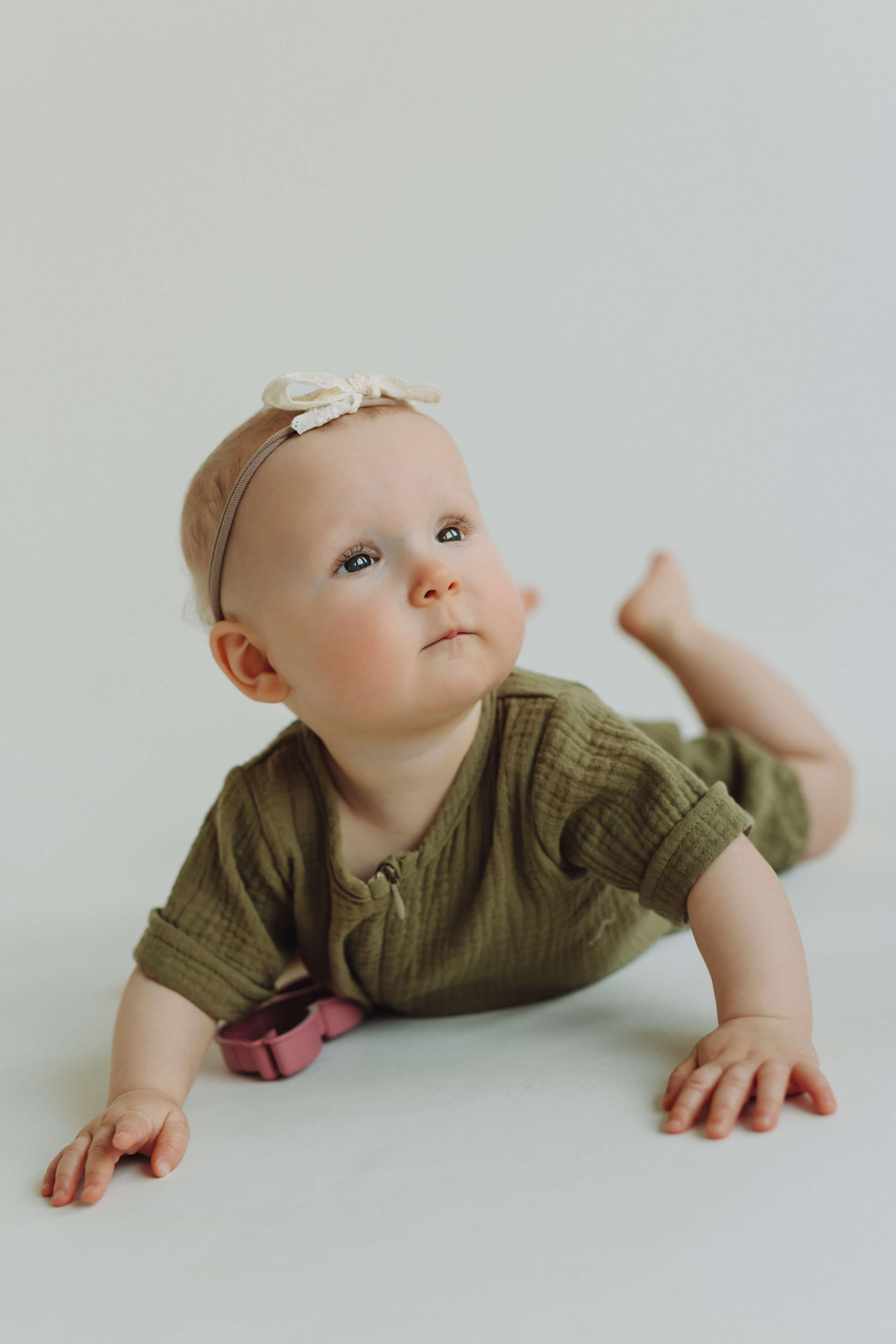 Baby in a green outfit and headband on a white background