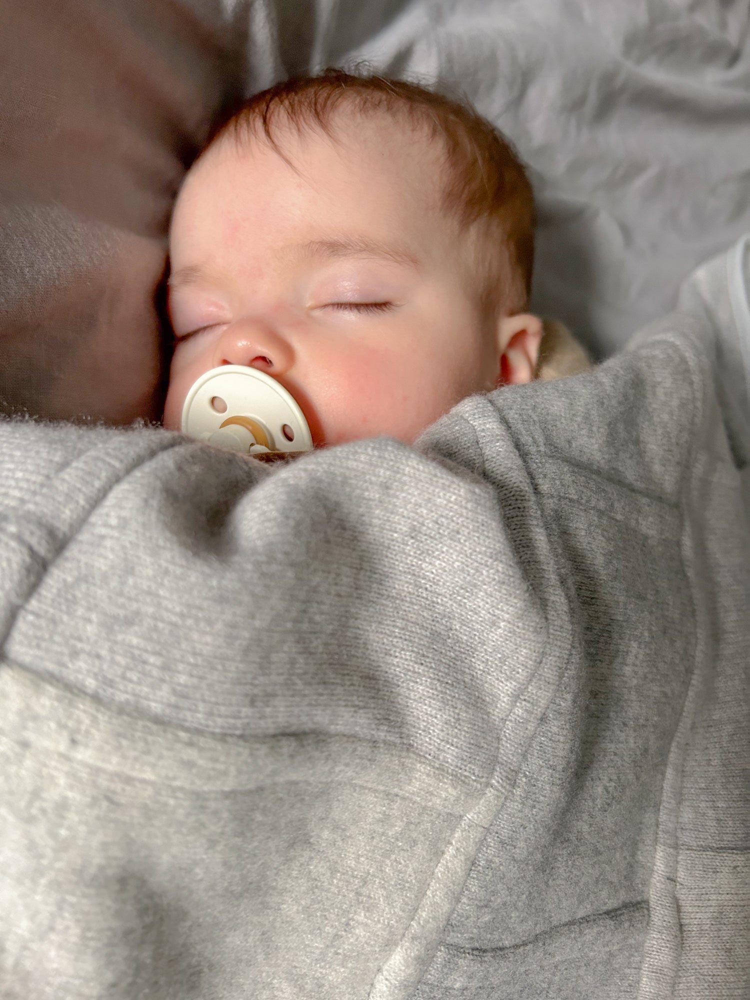 Sleeping baby wrapped in grey cashmere blanket