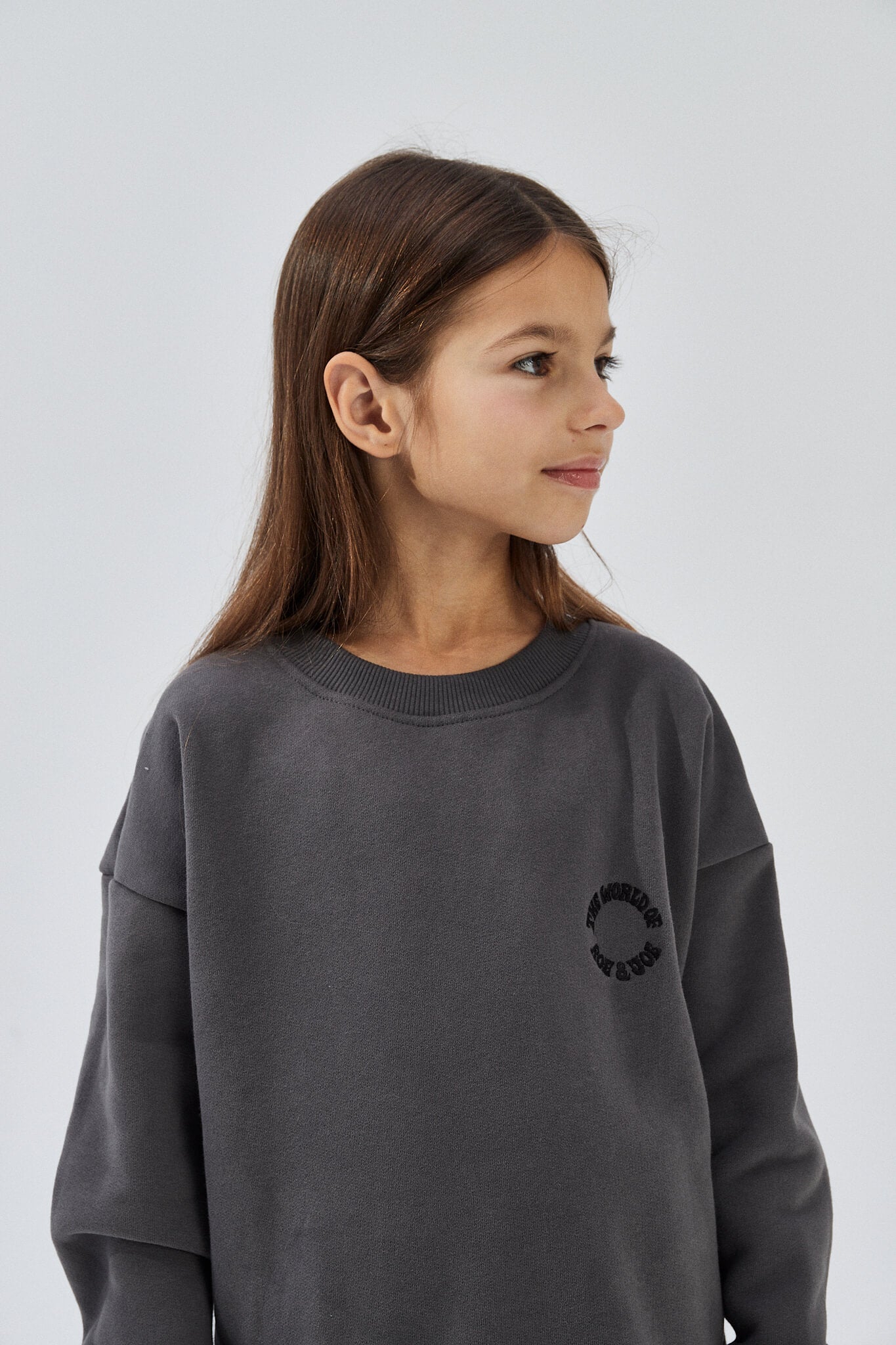 Child wearing a dark grey long-sleeve sweatshirt with a round neckline