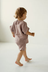 Child wearing a pink muslin outfit on a white background