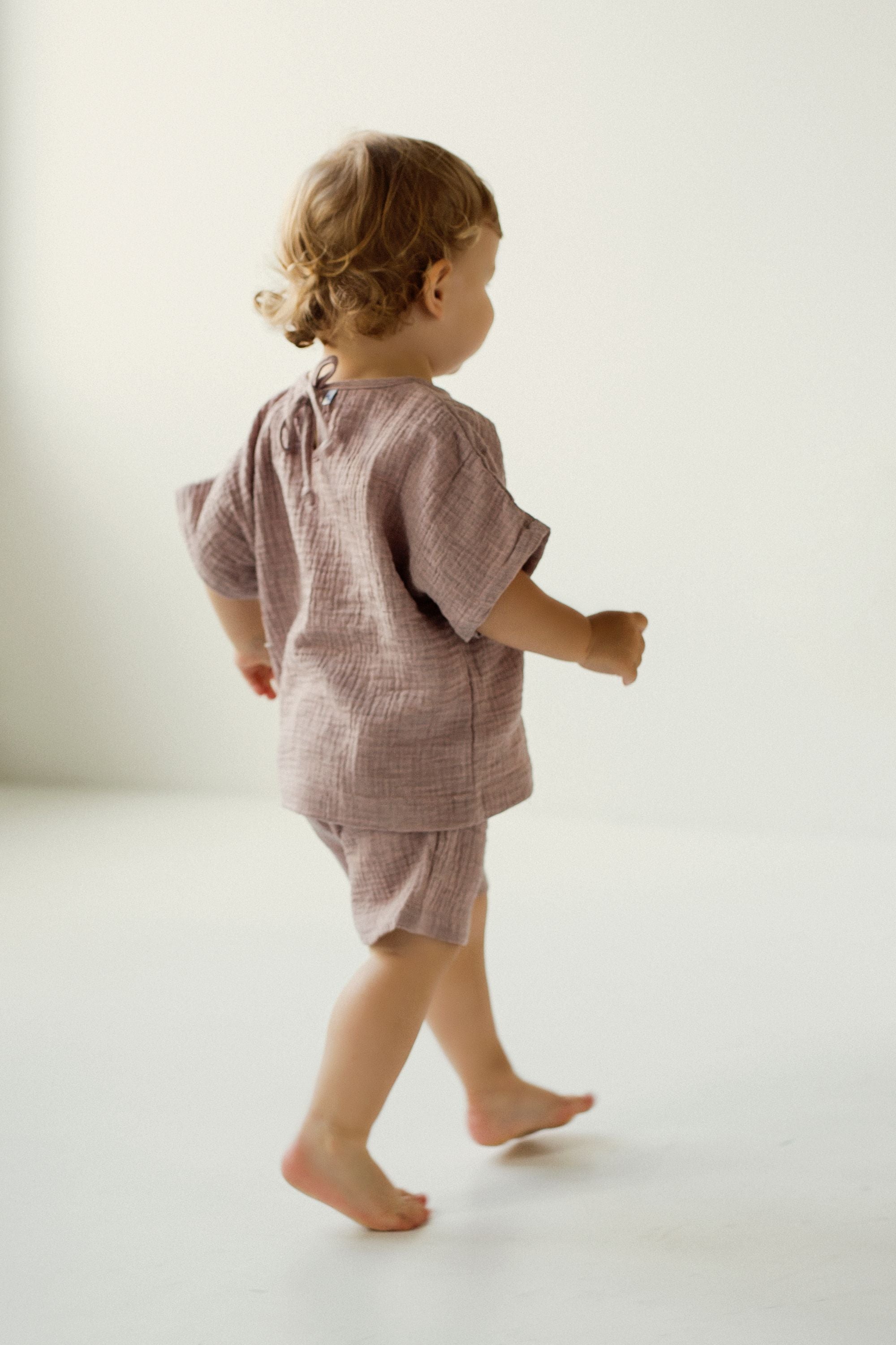 Child wearing a pink muslin outfit on a white background