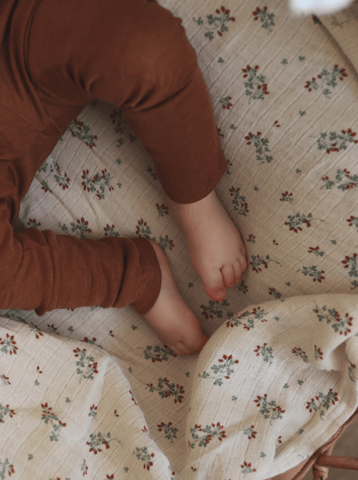 baby legs wearing brown leggins made from merino wool and silk on a blanket with flowers