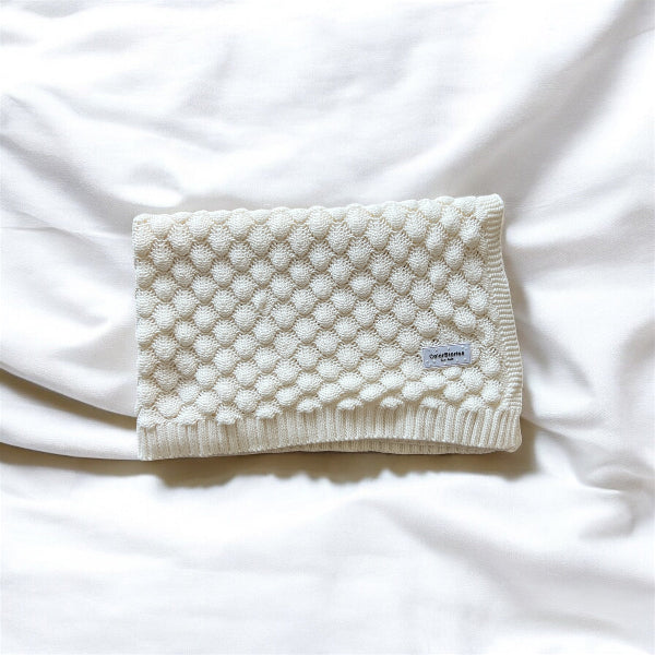 White textured blanket with a brand label on a white background