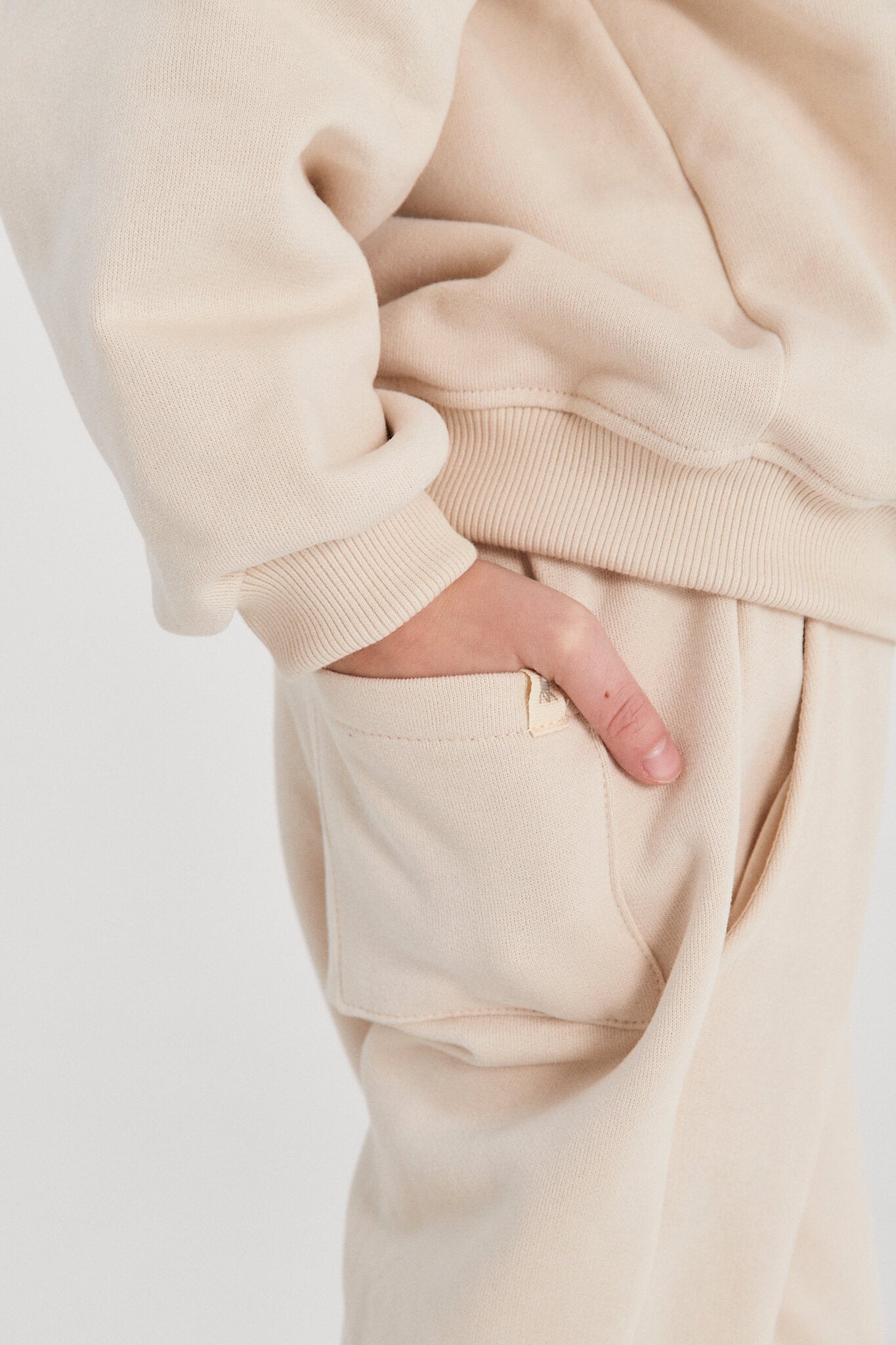 Beige sweatshirt and pants with a hand in the pocket
