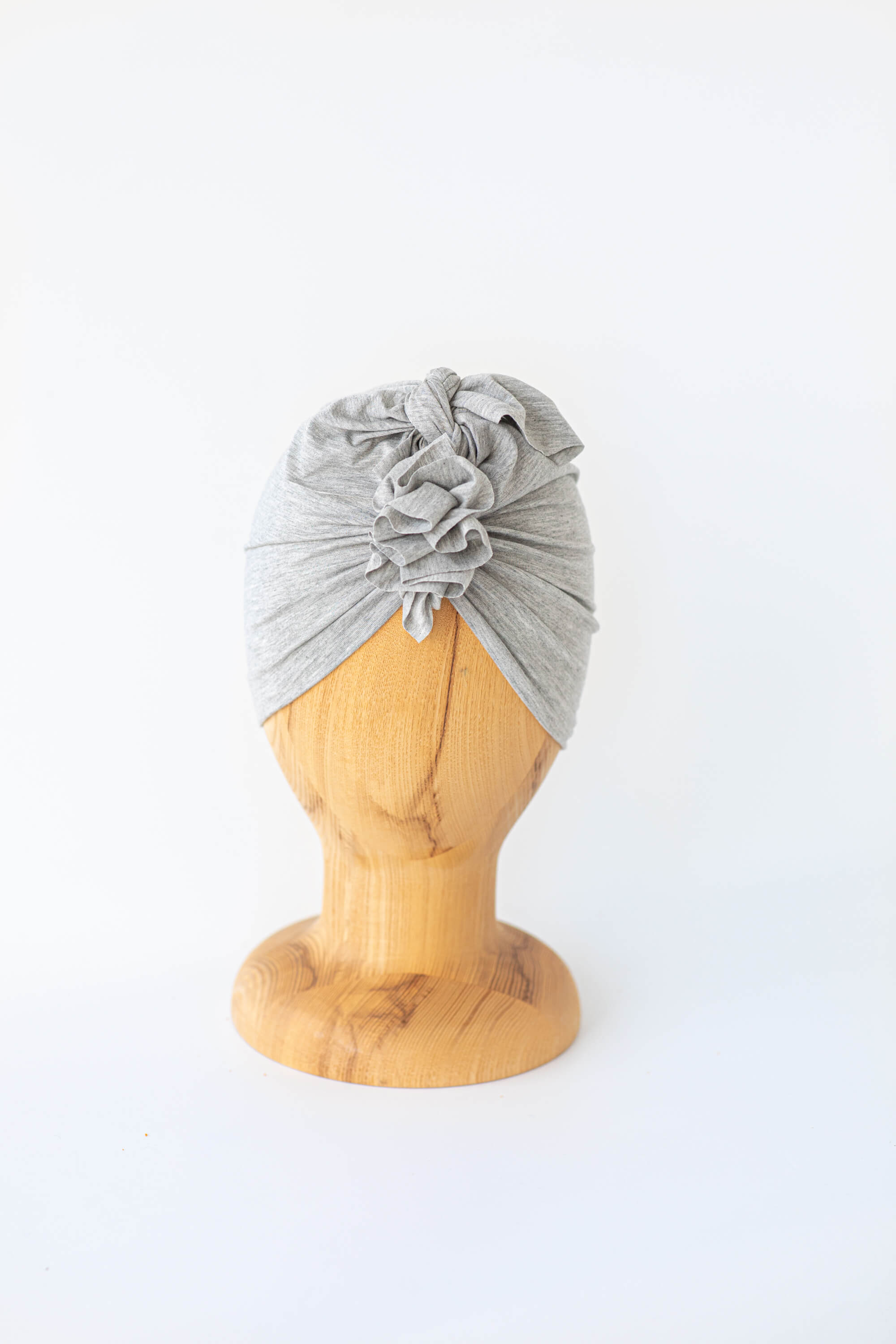 baby turban in color light grey on a wooden head mannequin on the white background