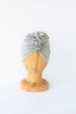 baby turban in color light grey on a wooden head mannequin on the white  background