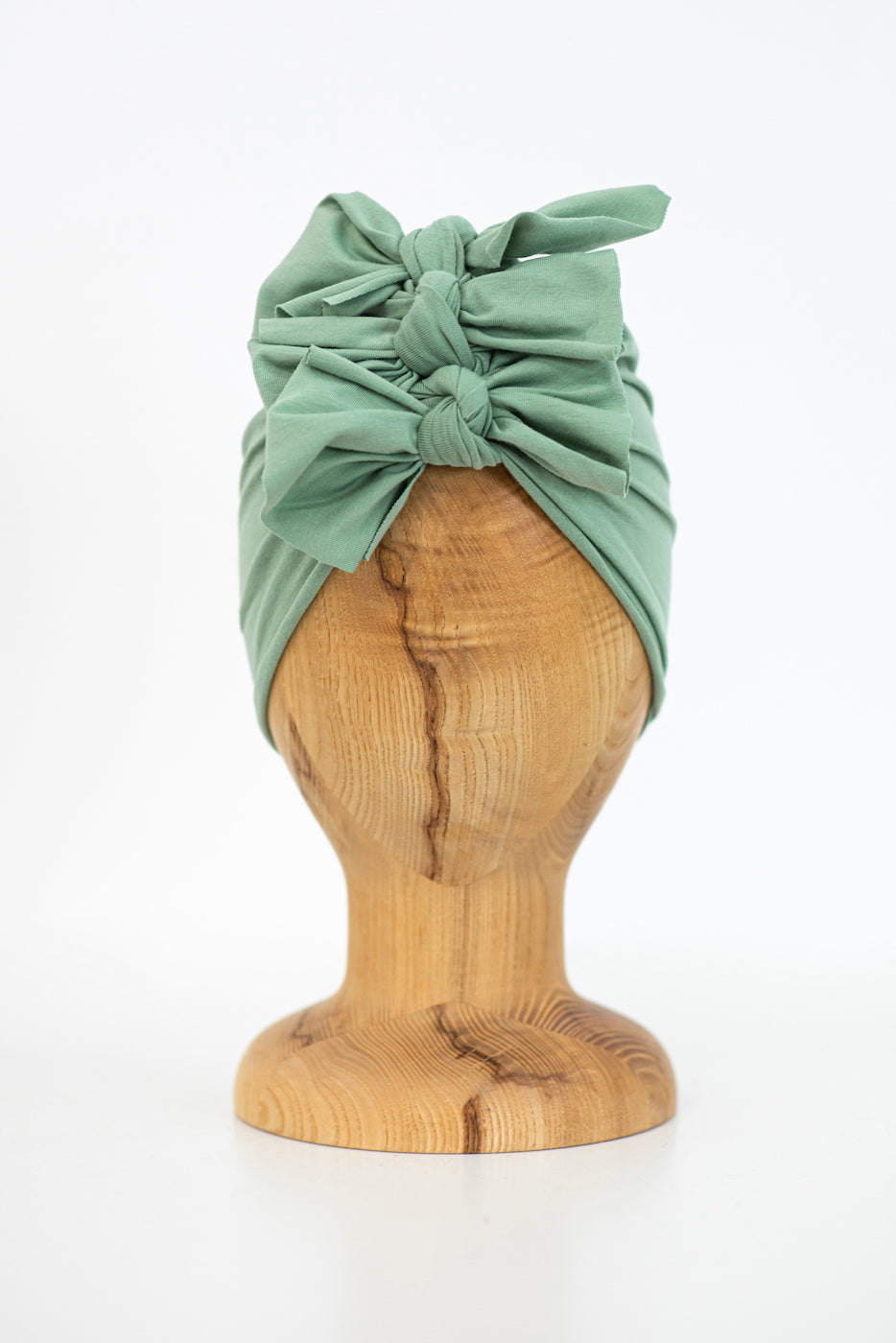 a vintage mint kids turban on a wooden mannequin with a plan white background