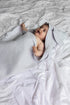 Baby wrapped in a gray blanket lying on a white bed