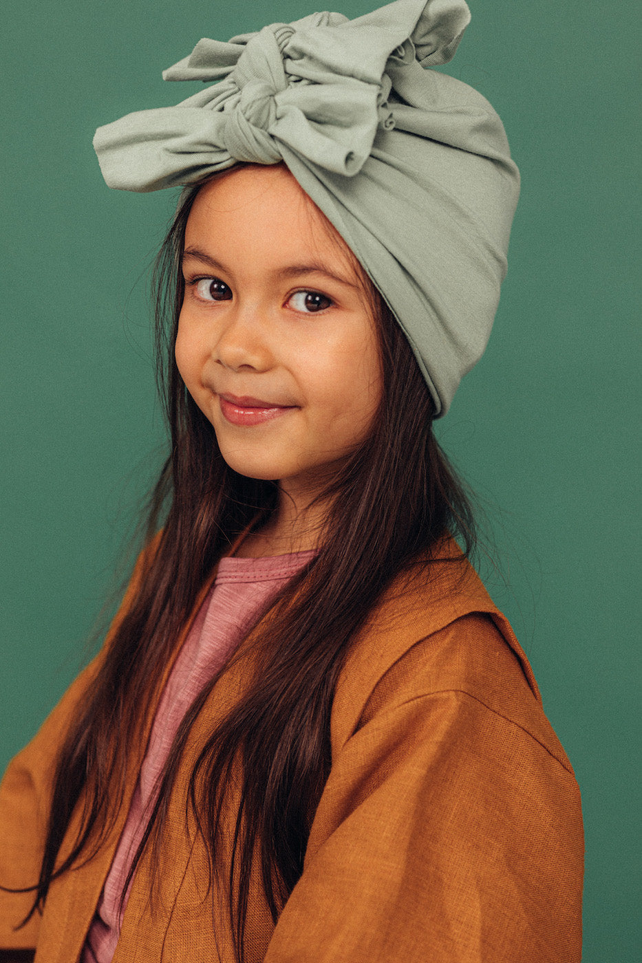 A girl with long brown hair wearing a vintage mint turban