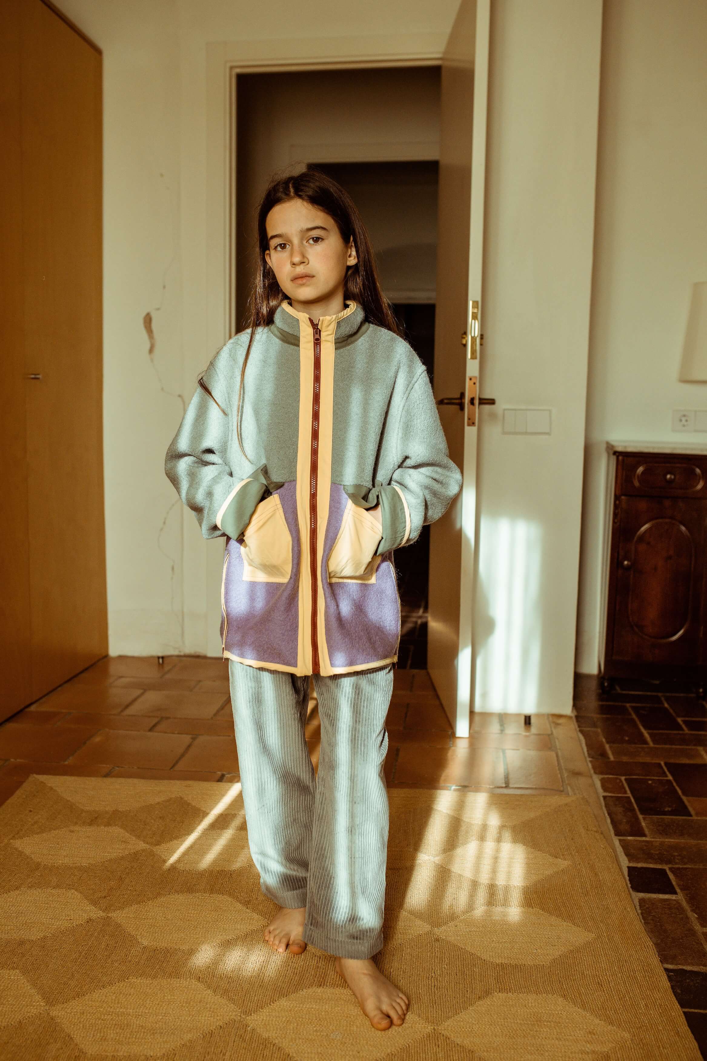 Child wearing a colorful tracksuit standing in a room