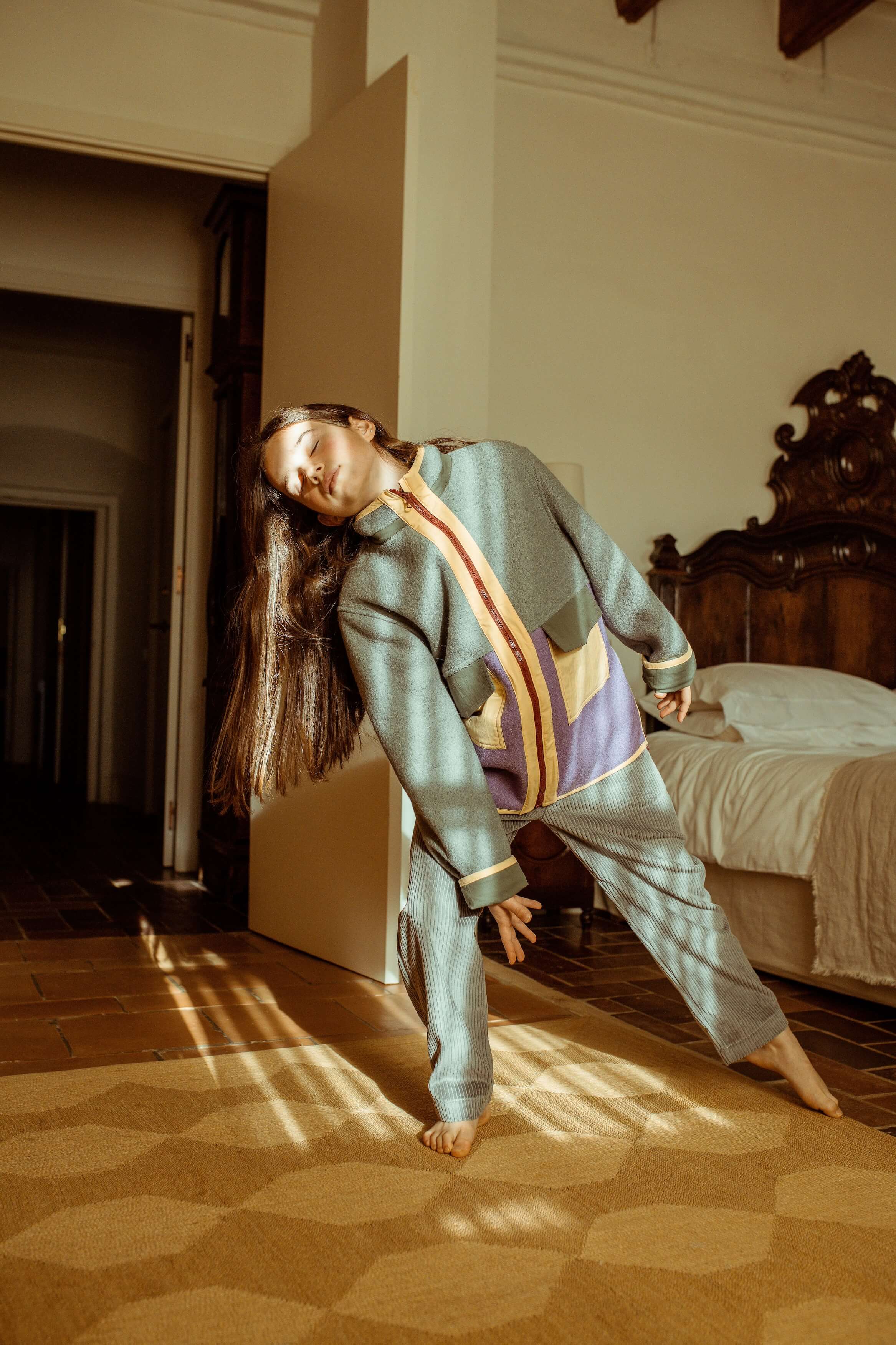 Woman in a patterned outfit standing in a sunlit room