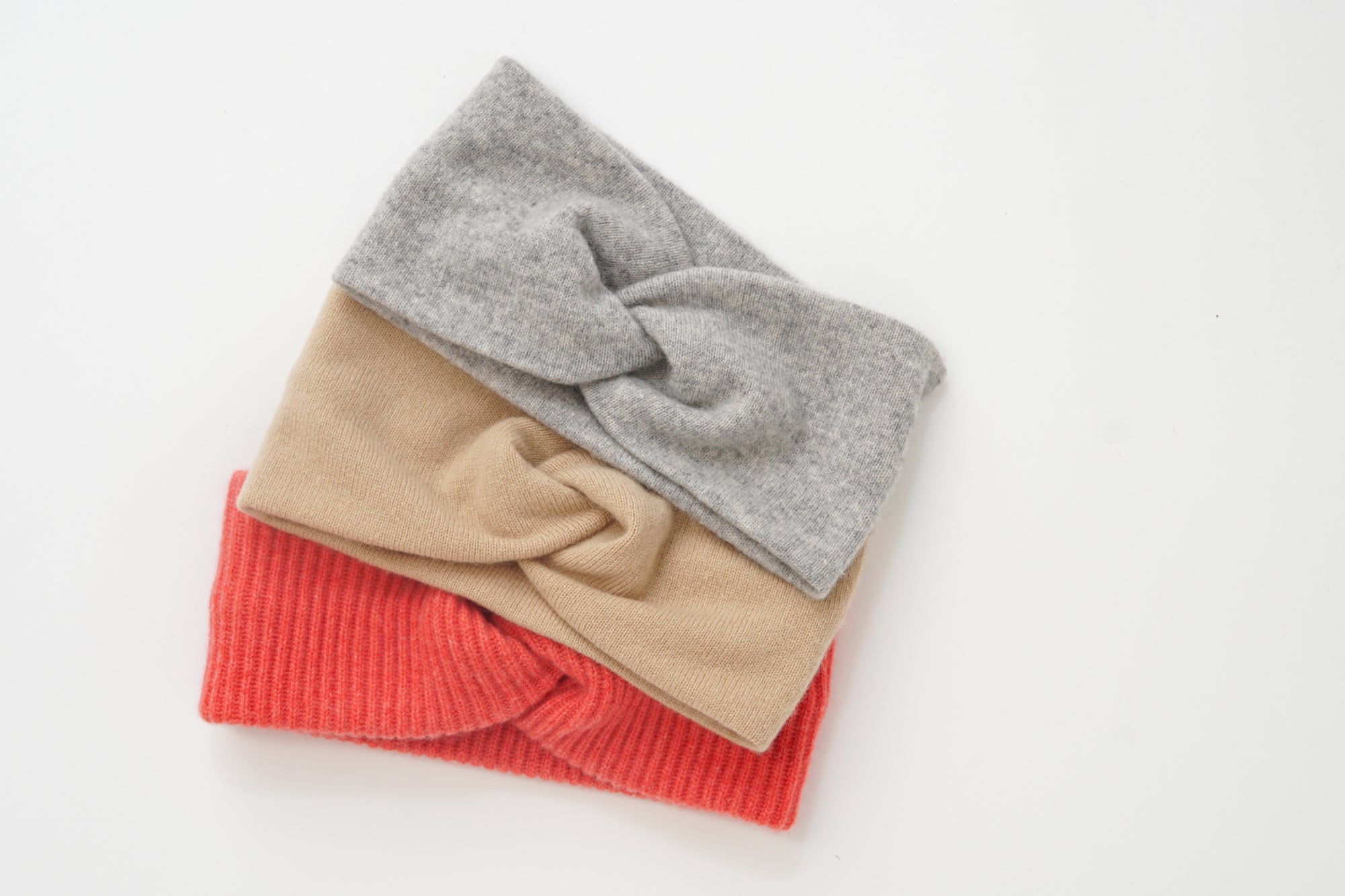 Stack of folded sweaters in gray, beige, and red