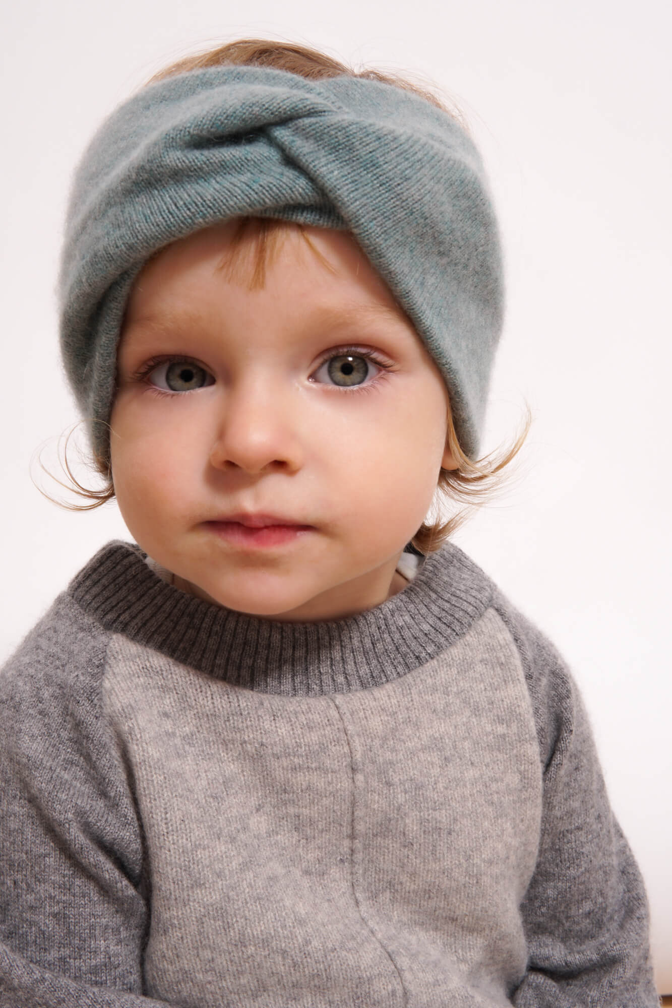 Child wearing a gray knit headband and sweater
