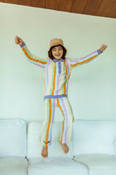 A person jumping in the air wearing striped cotton culotte pants and a matching sweatshirt, with arms raised and a happy expression.