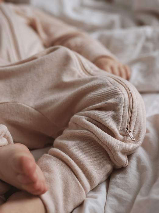 baby legs wearing beige overall with a zipper