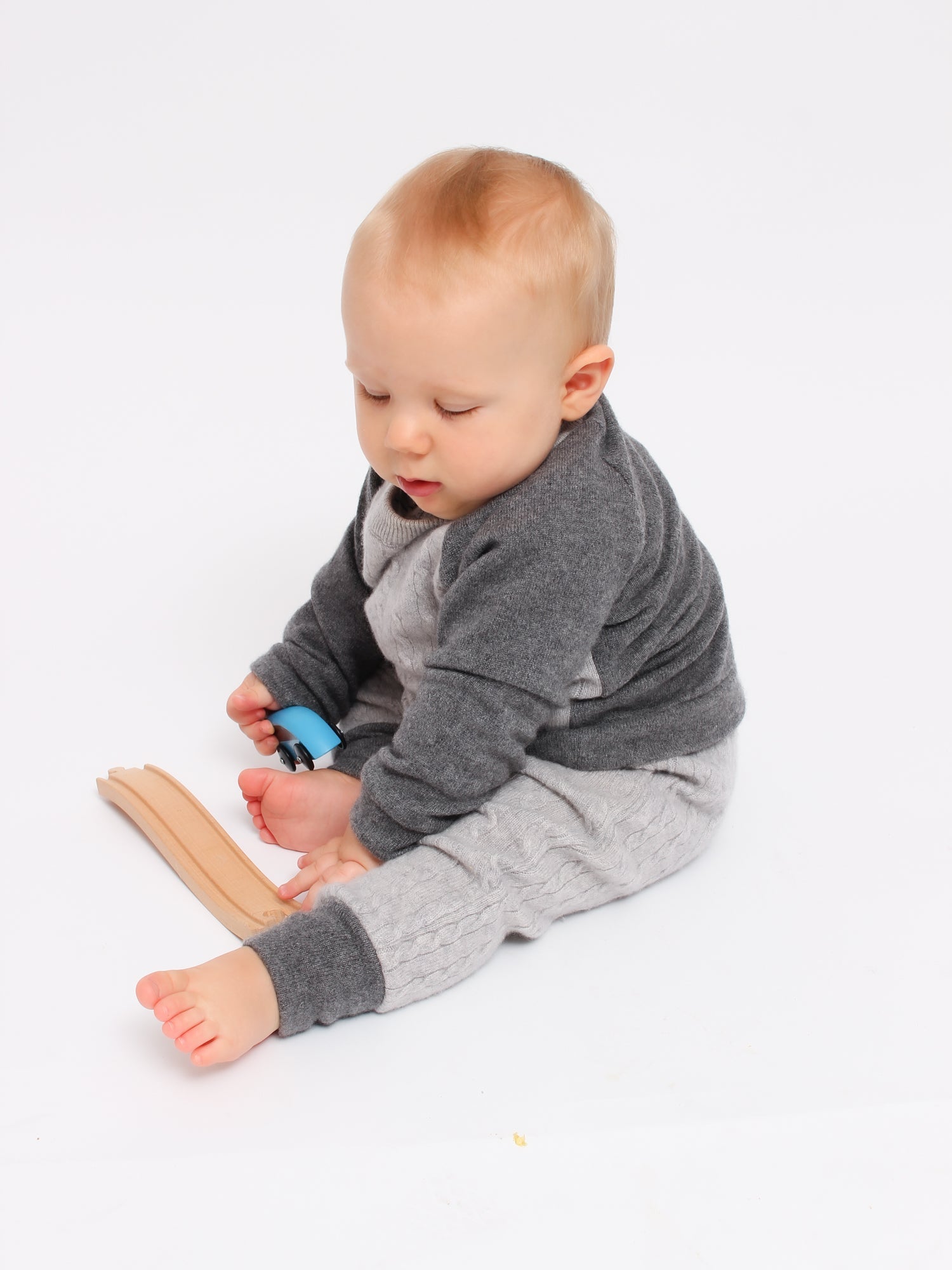 baby playing with toys wearing pure cashmere set of pants and sweater made of pure cashmere in color grey