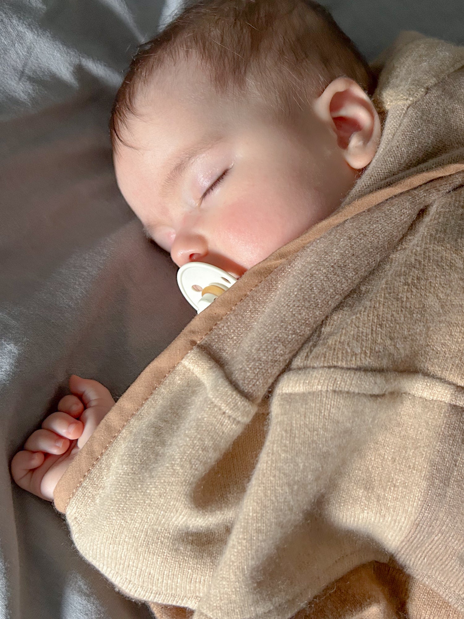 baby wrapped in beige cashmere baby blanket