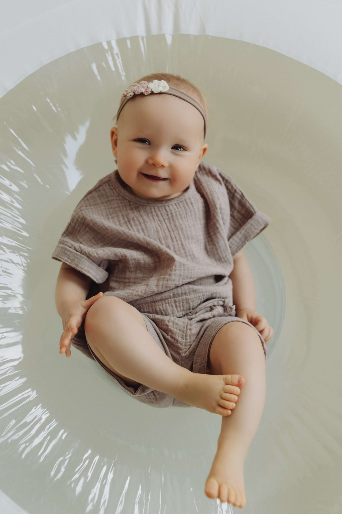 Baby in a pink outfit sitting in a white circular chair