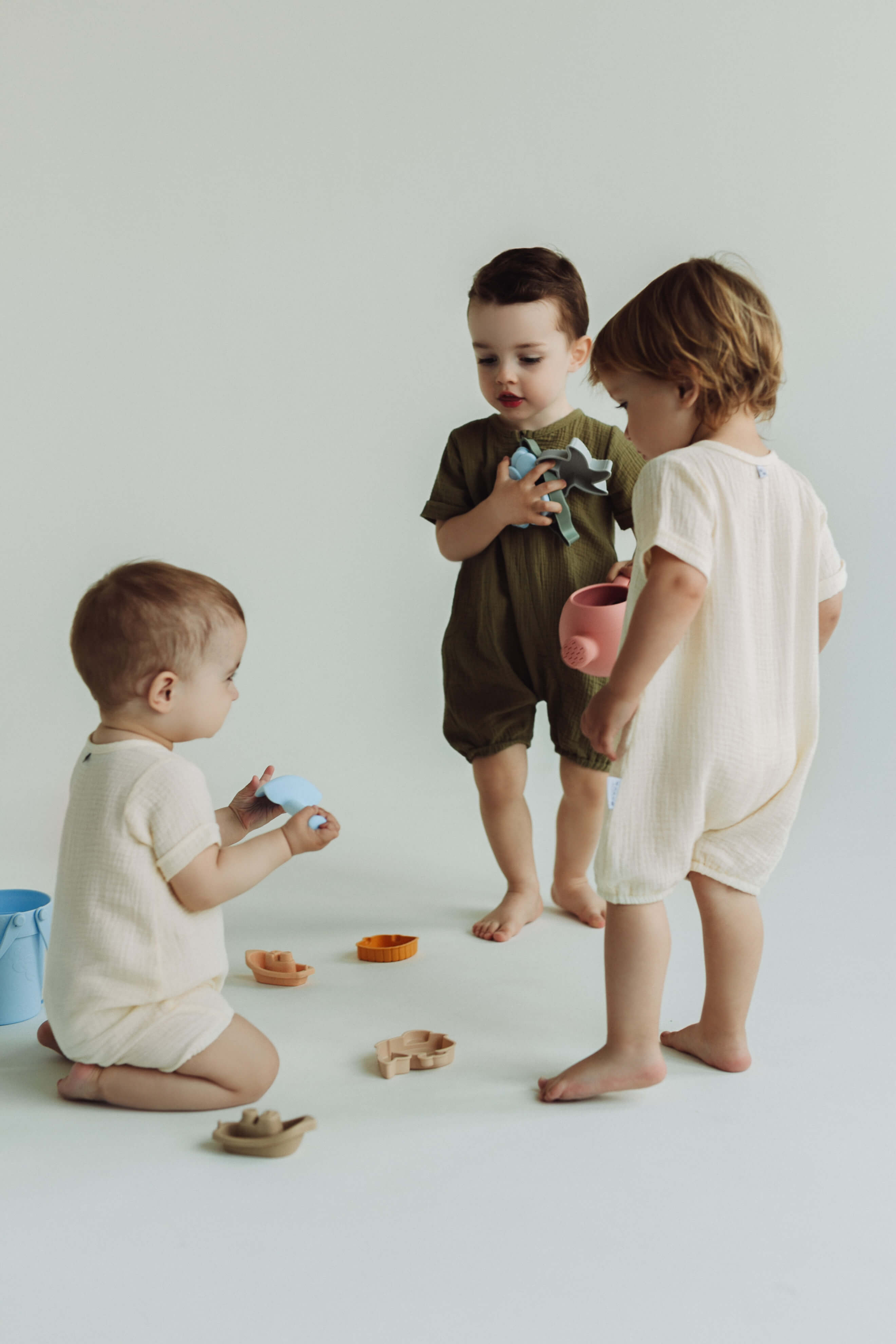 Three children playing with toys on a light-colored floor.