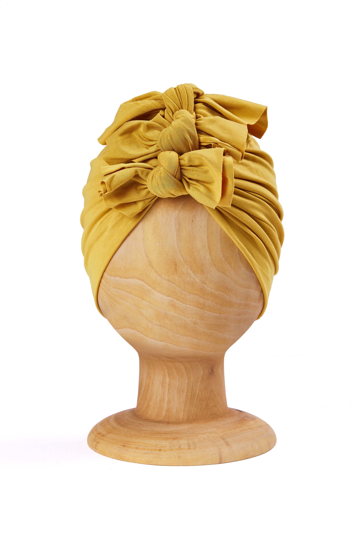 Bamboo baby turban in a warm yellow color on a wooden mannequin