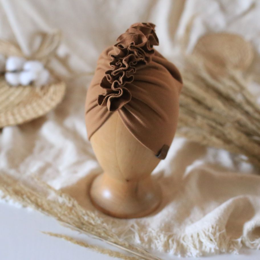 baby turban in color caramel on a wooden head mannequin 