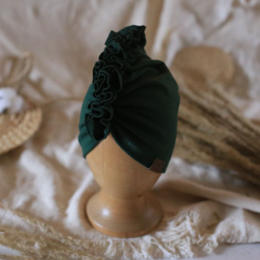 baby turban in color dark green on a wooden head mannequin 