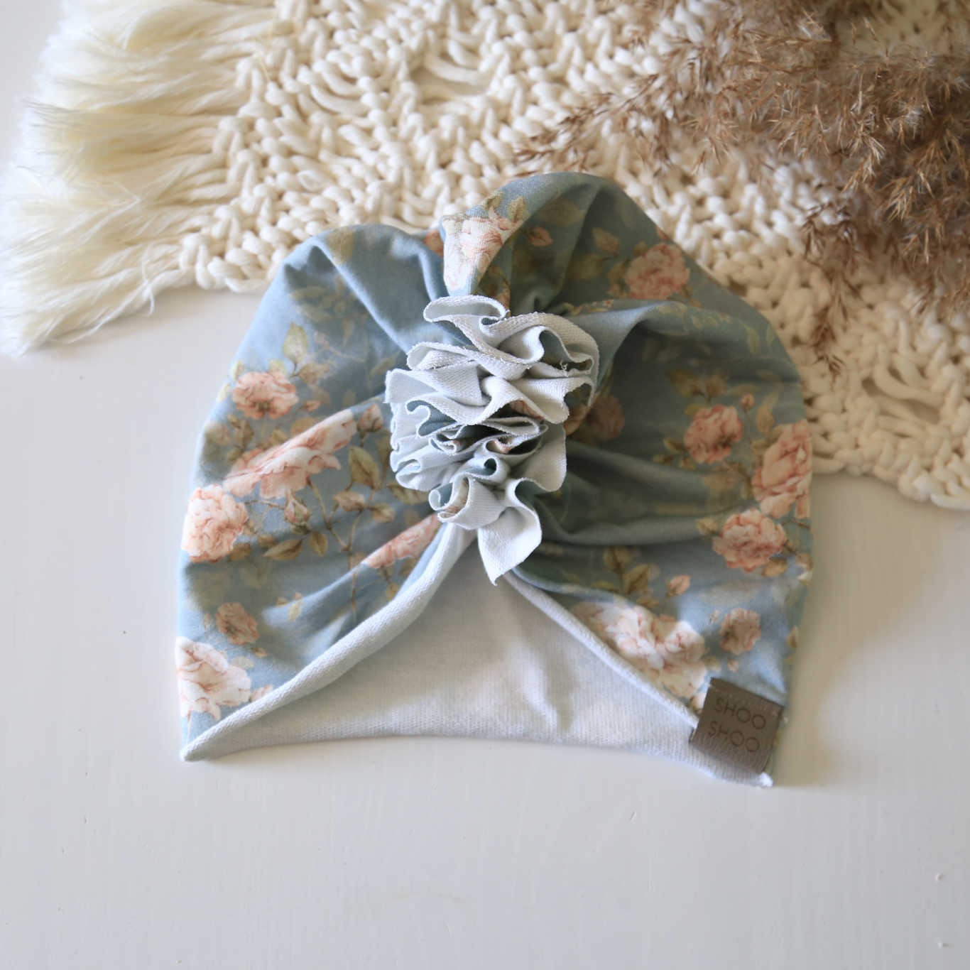 baby turban in light blue color with a floral print on it