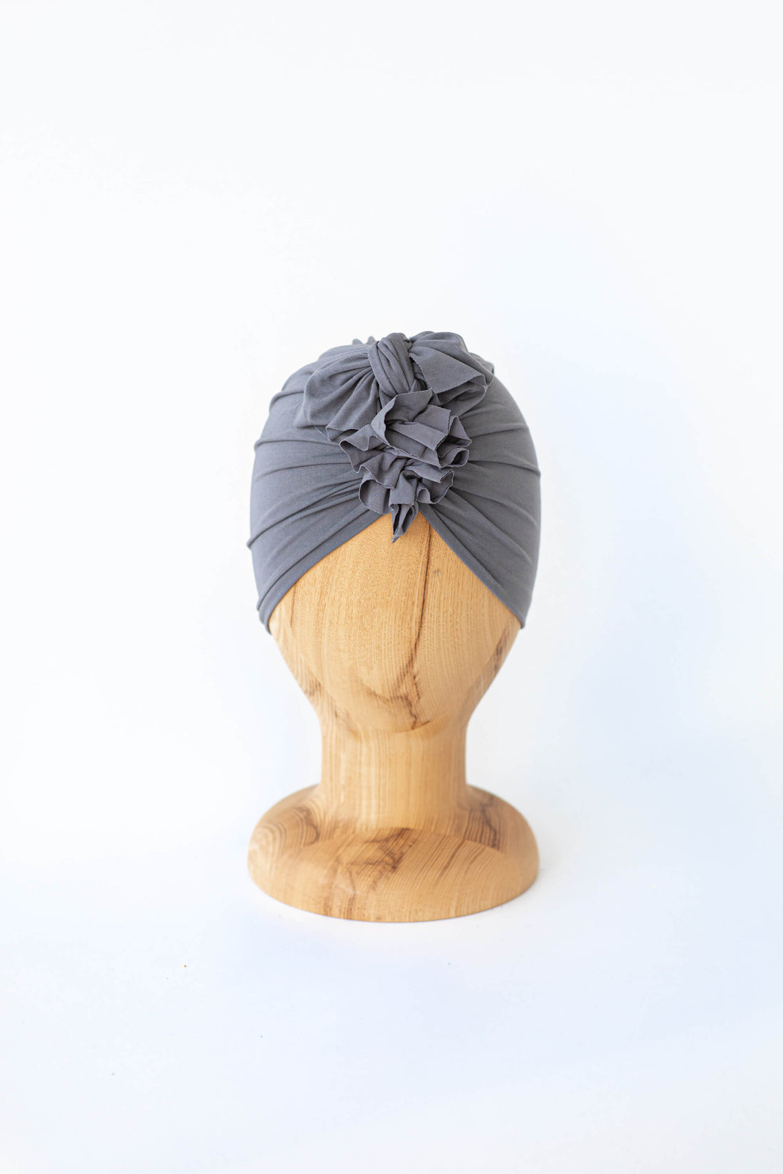 baby turban in color grey on a wooden head mannequin on a white plain background