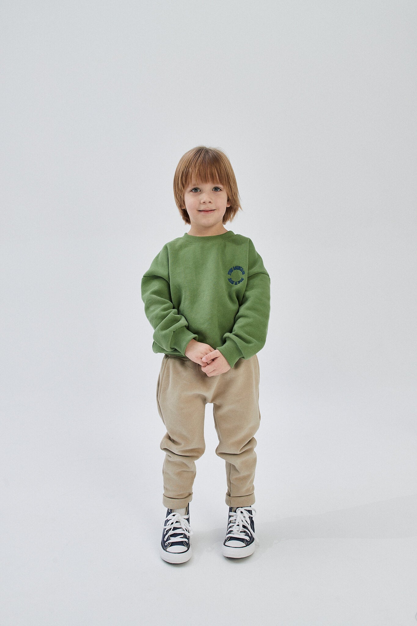 A child wearing green sweatpants and a green sweatshirt, with beige sweatpants suggested as an alternative option