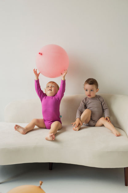 2 Kinder auf dem Sofa. Das erste Kind spielt mit dem Balloon, das zweite sitzt auf dem Sofa