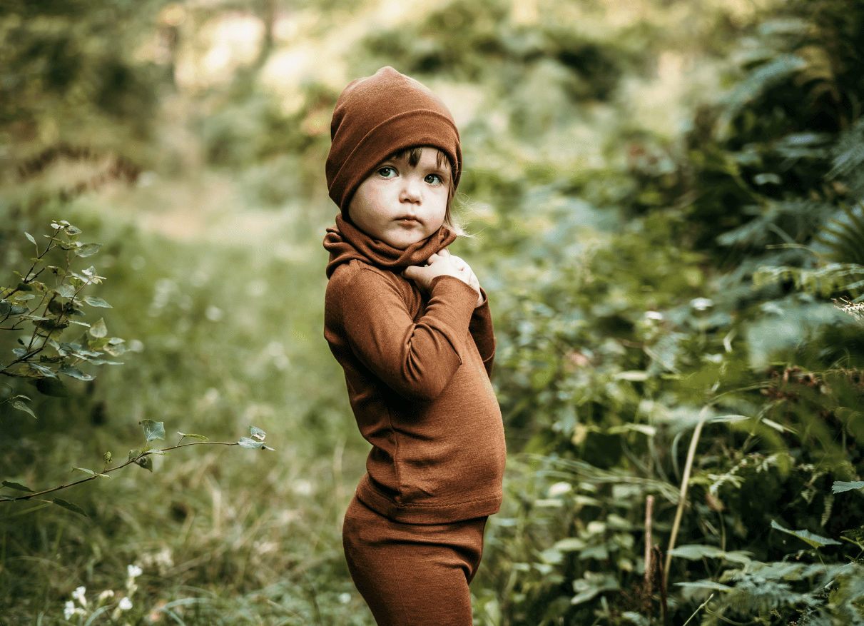 small girl in the forest wearing brown merino wool and silk leggins, tshirt and hat