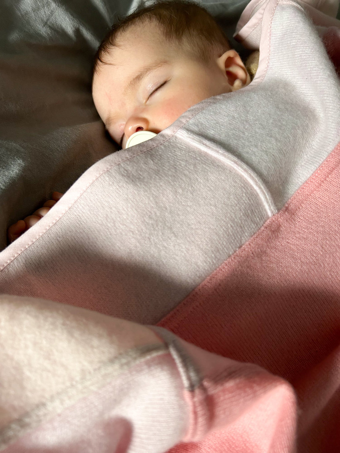 Sleeping baby wrapped in 100% cashmere baby blanket made of rectangular patches in color pink