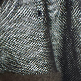 Close-up of a textured fabric surface with a hand holding it.