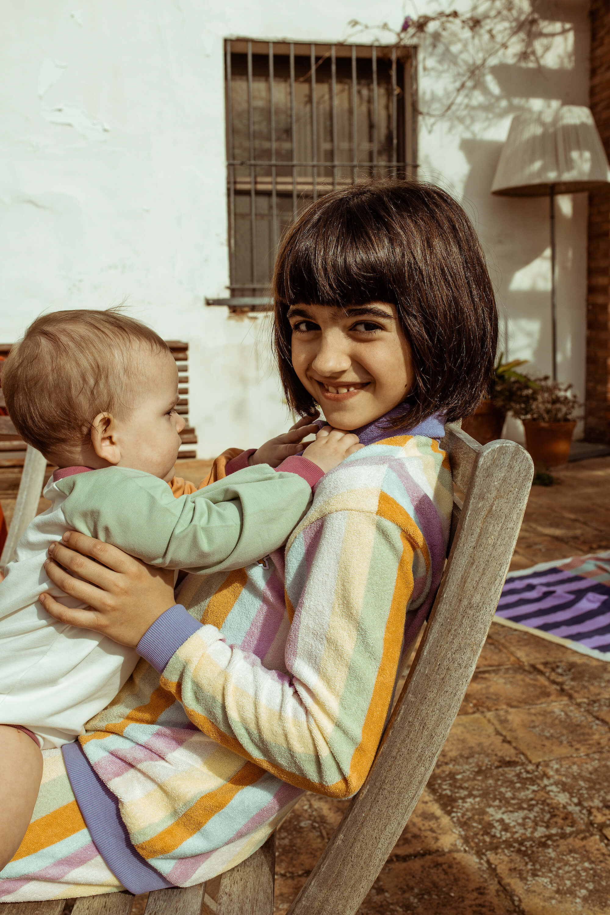 girl holding a baby outdoors in a casual setting
