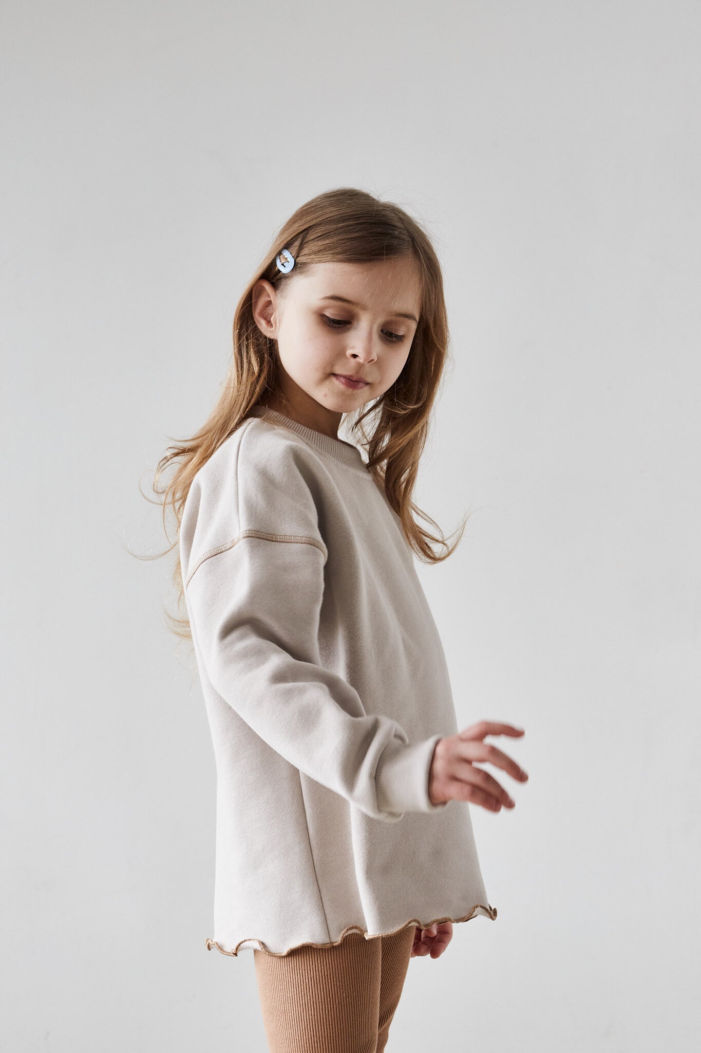 Girl wearing beige sweatshirt and beige leggings on a white background