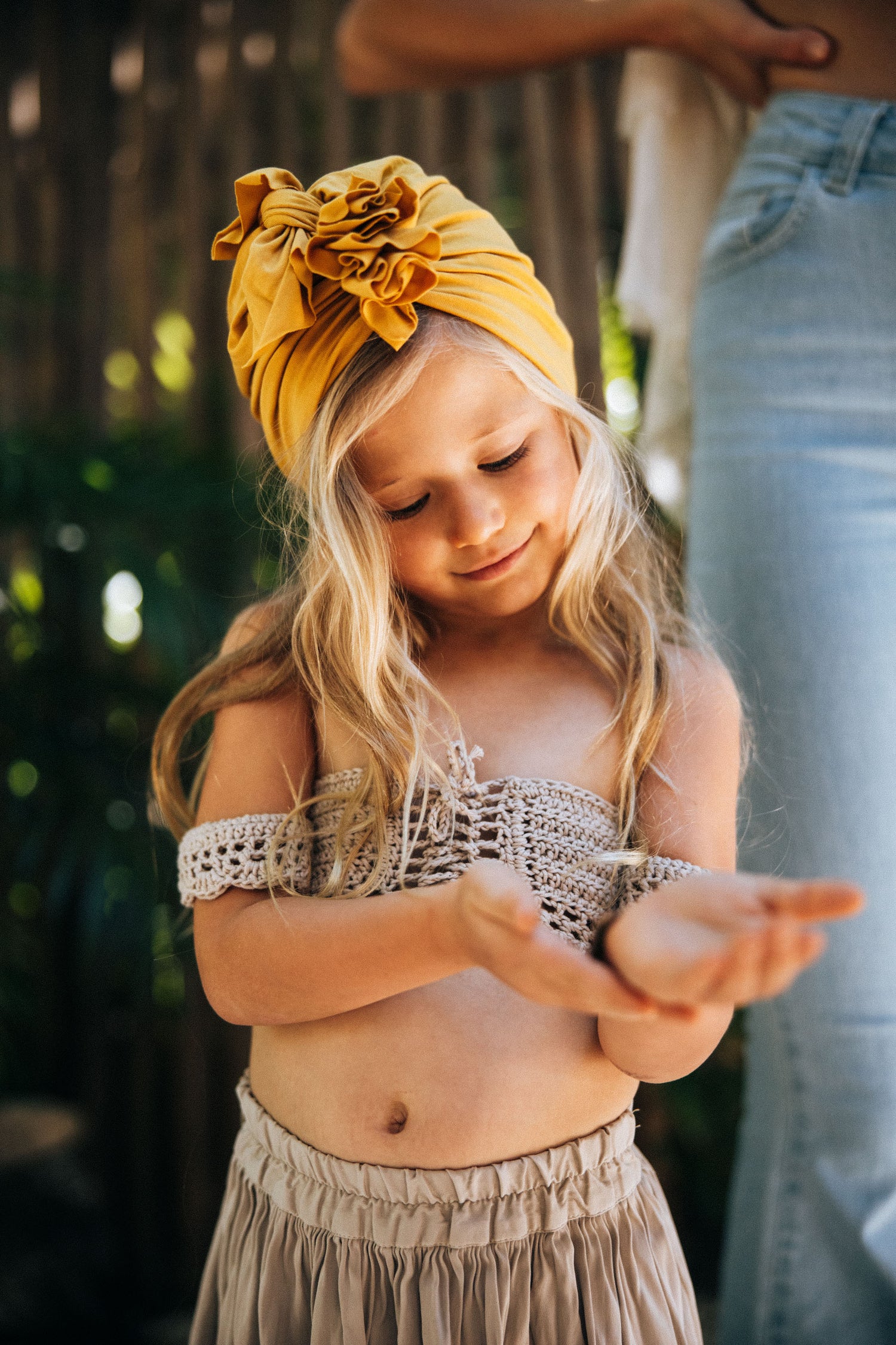 A 5 year old girl wearing a skirt and a top and yellow turban