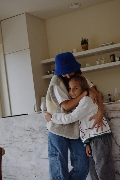 Two people hugging in a room with shelves and decor.