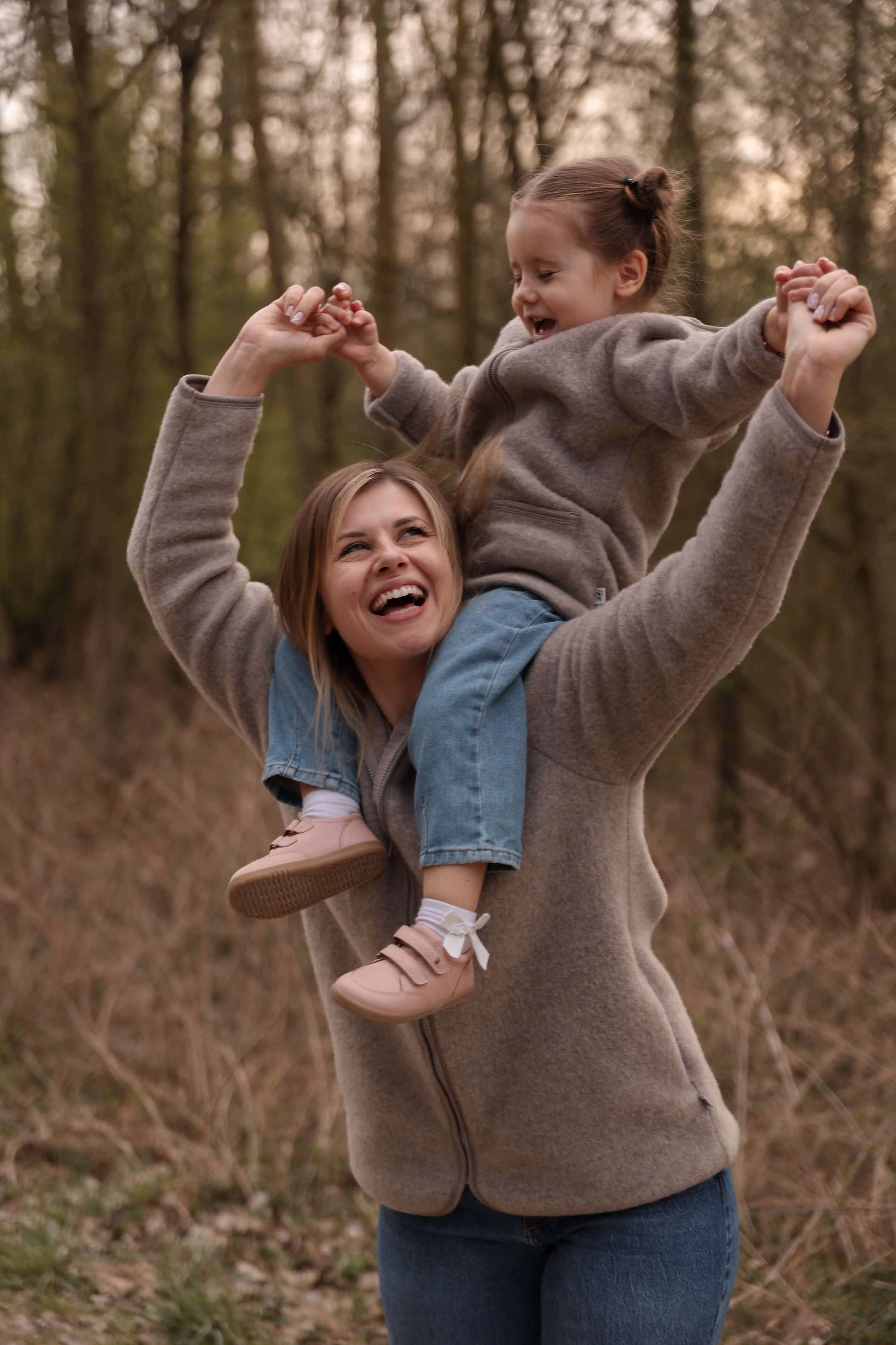 Woman holding a child on her shoulders in a forest setting
