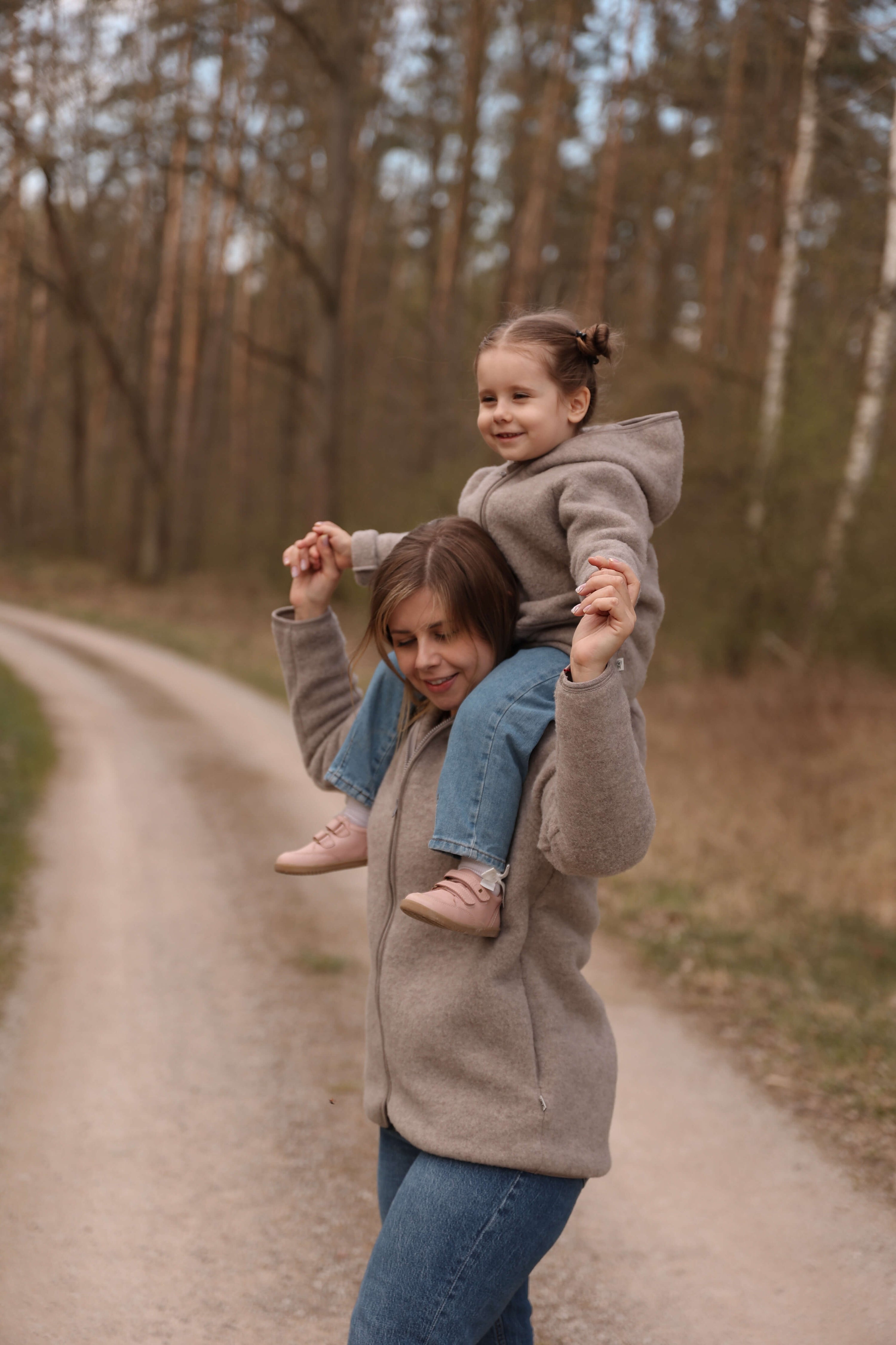 Woman holding a child on a dirt path in a forest