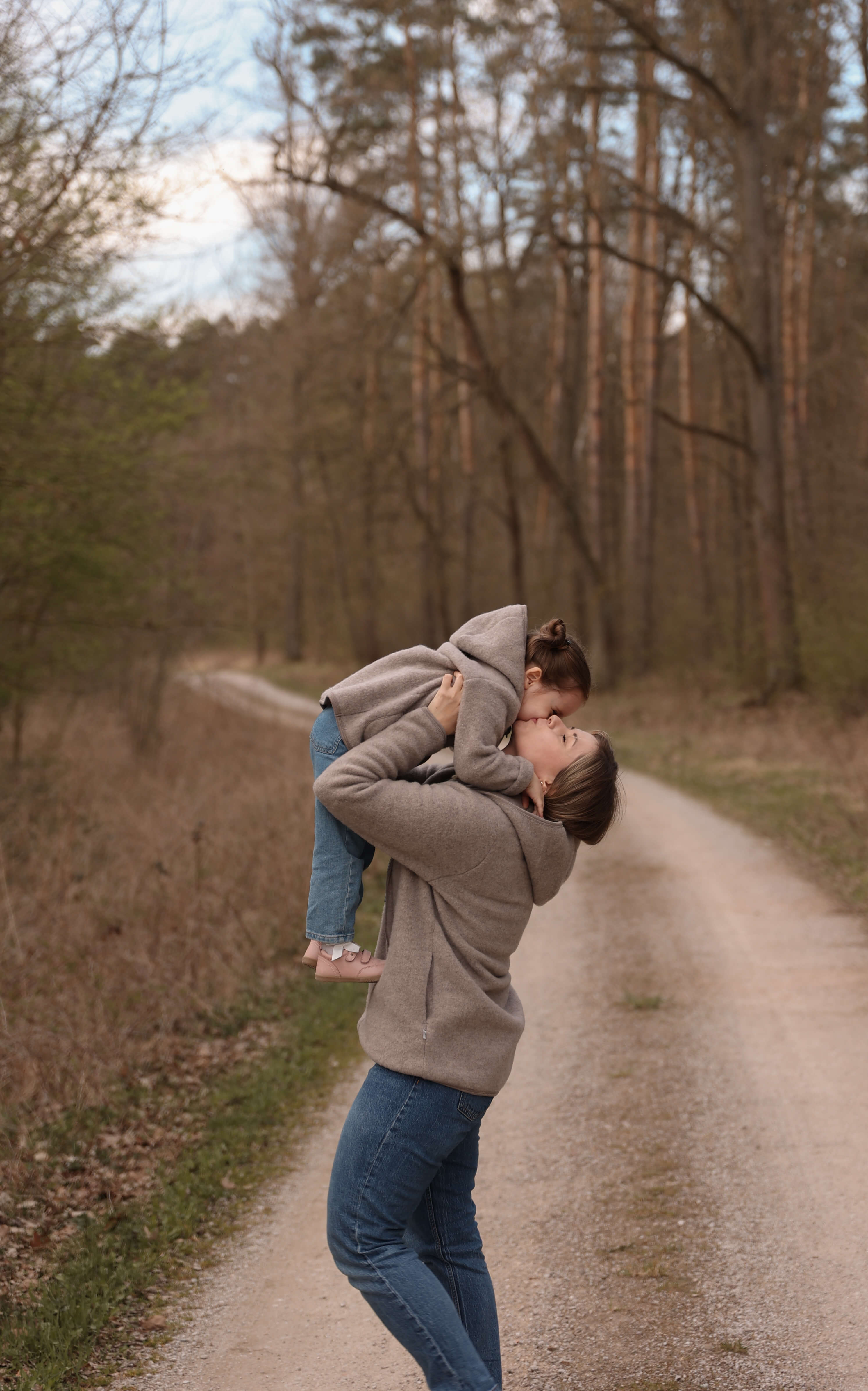 Woman lifting a child in a forest path
