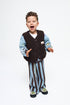 Child wearing a brown vest and striped pants on a white background