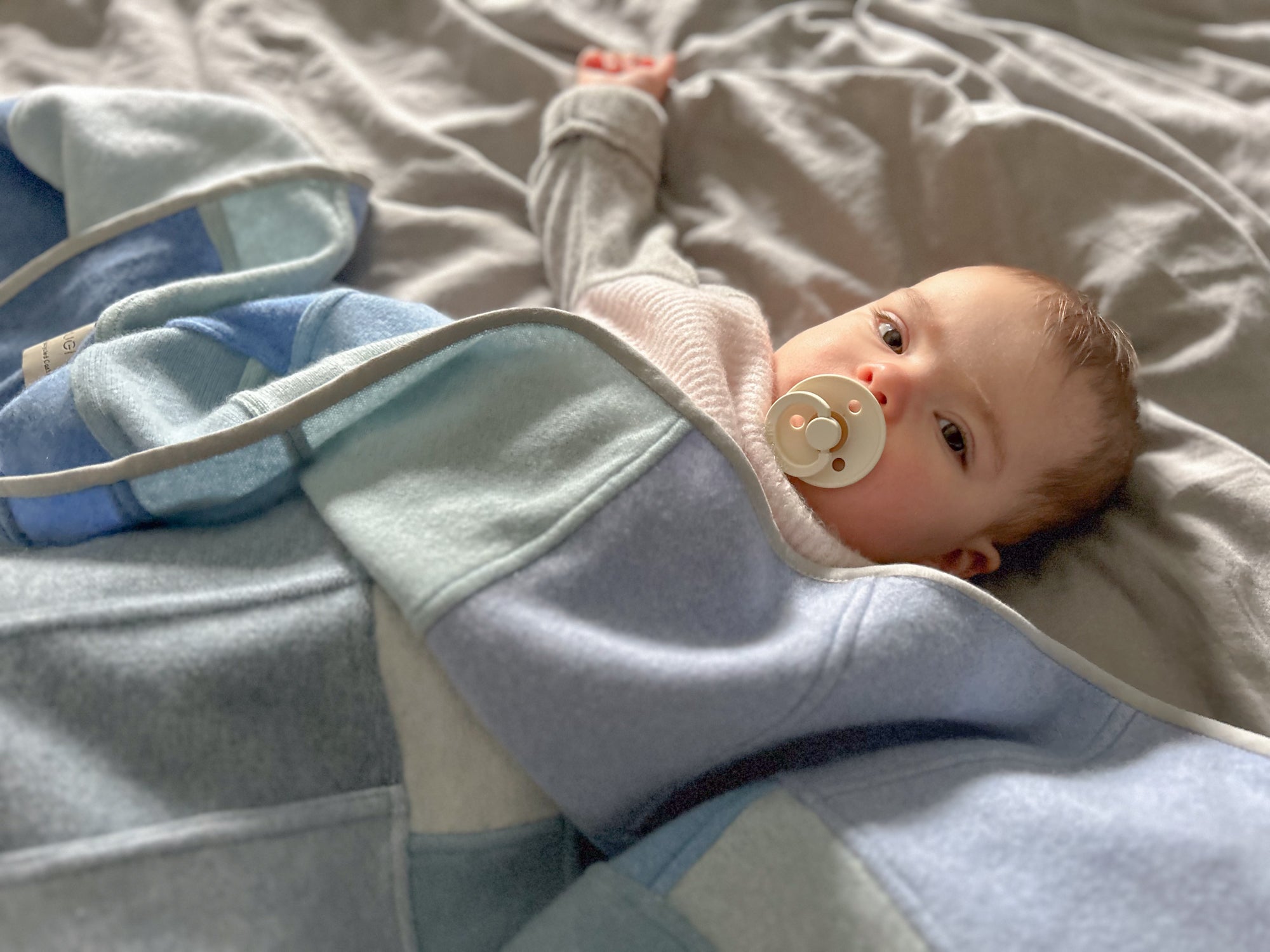 Baby unter der blauen Kaschmirdecke auf dem Bett