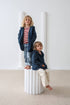 Two children wearing matching navy blue hoodies in a minimalistic setting